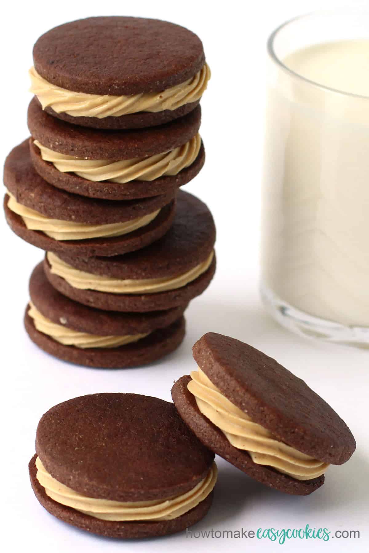 Homemade chocolate sandwich cookies filled with peanut butter fudge served with a glass of milk.