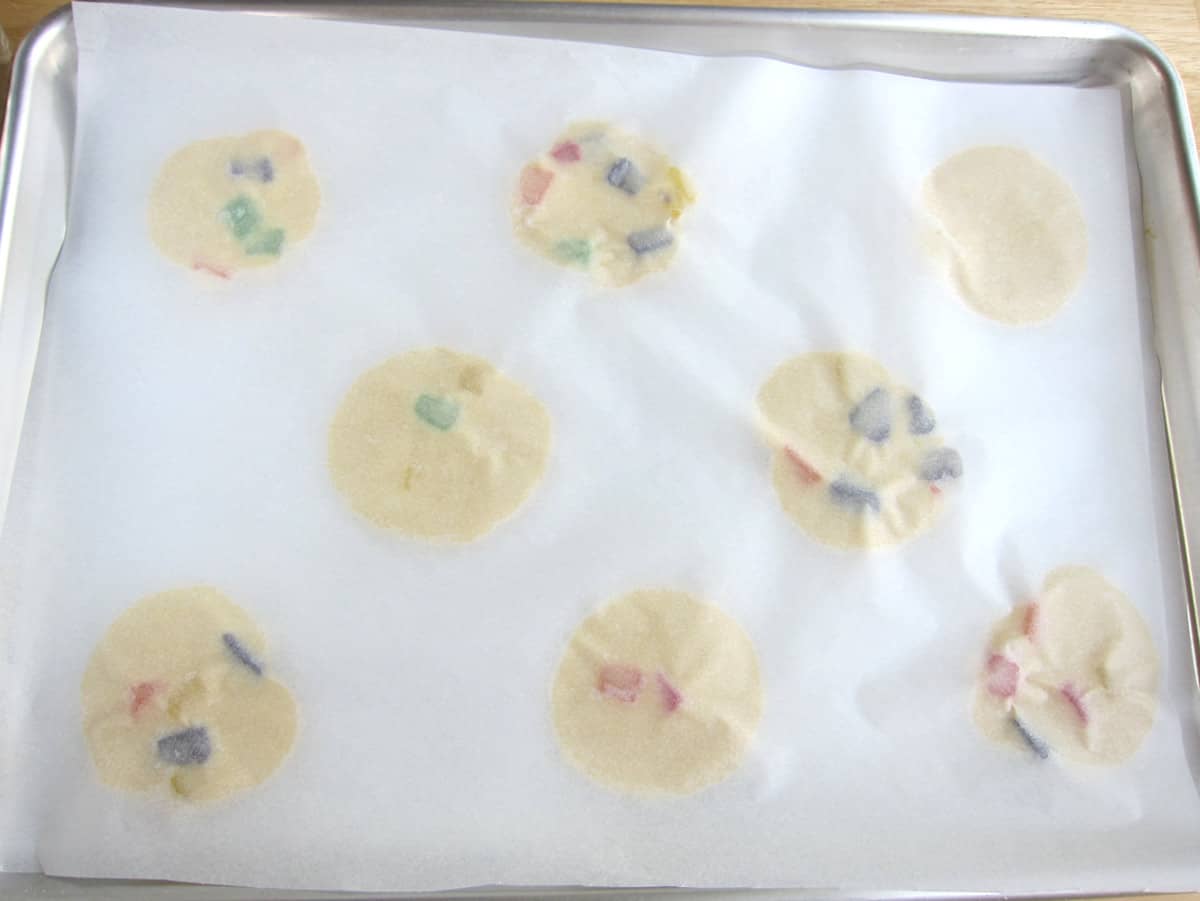 Flattened gumdrop cookies covered with parchment paper. 
