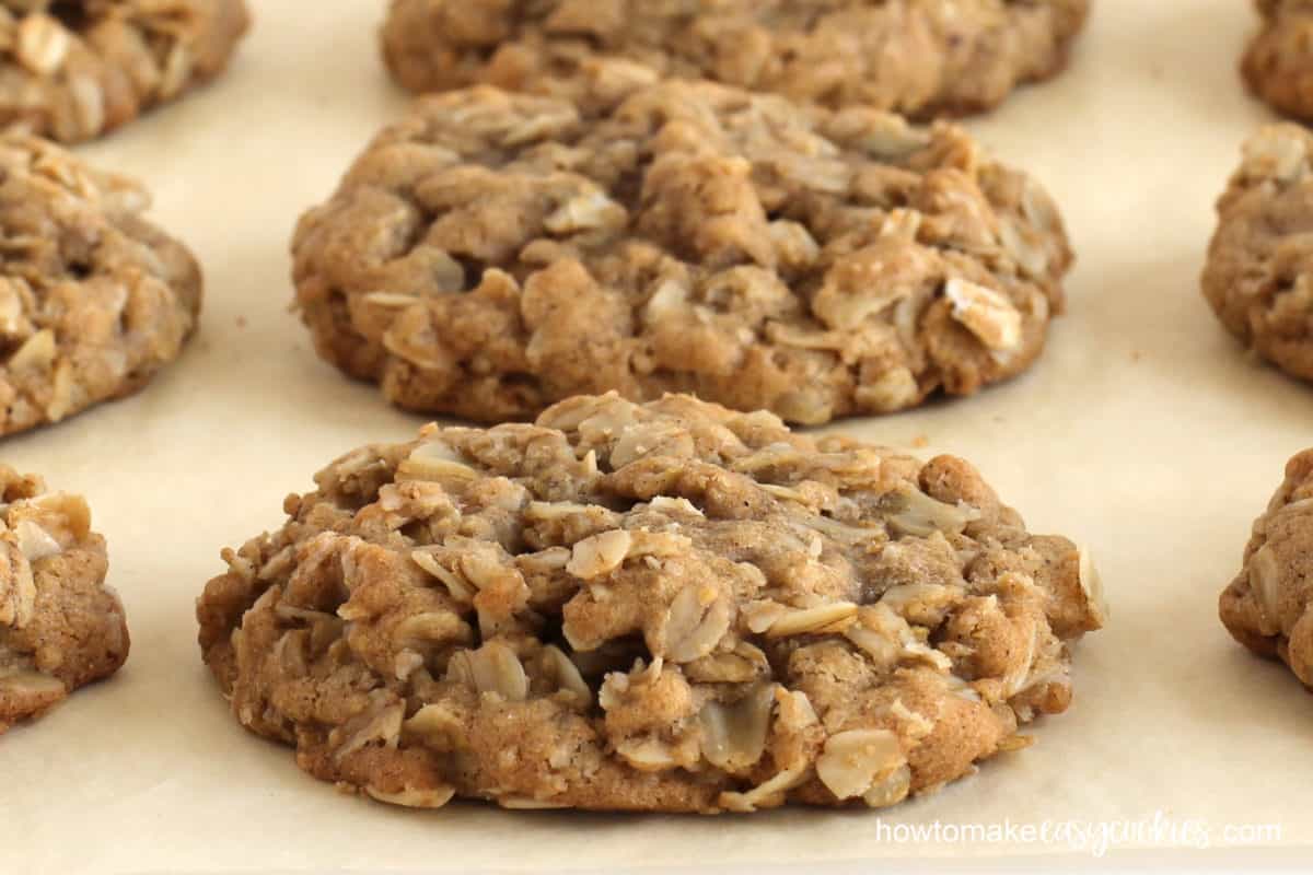 Oatmeal cookies filled with old-fashioned oats are baked on parchment paper.