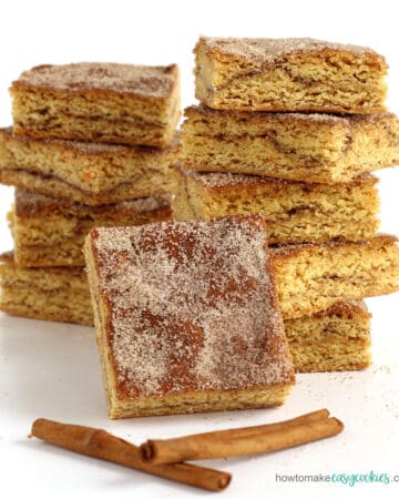 cake mix snickerdoodle cookie bars stacked next to cinnamon sticks