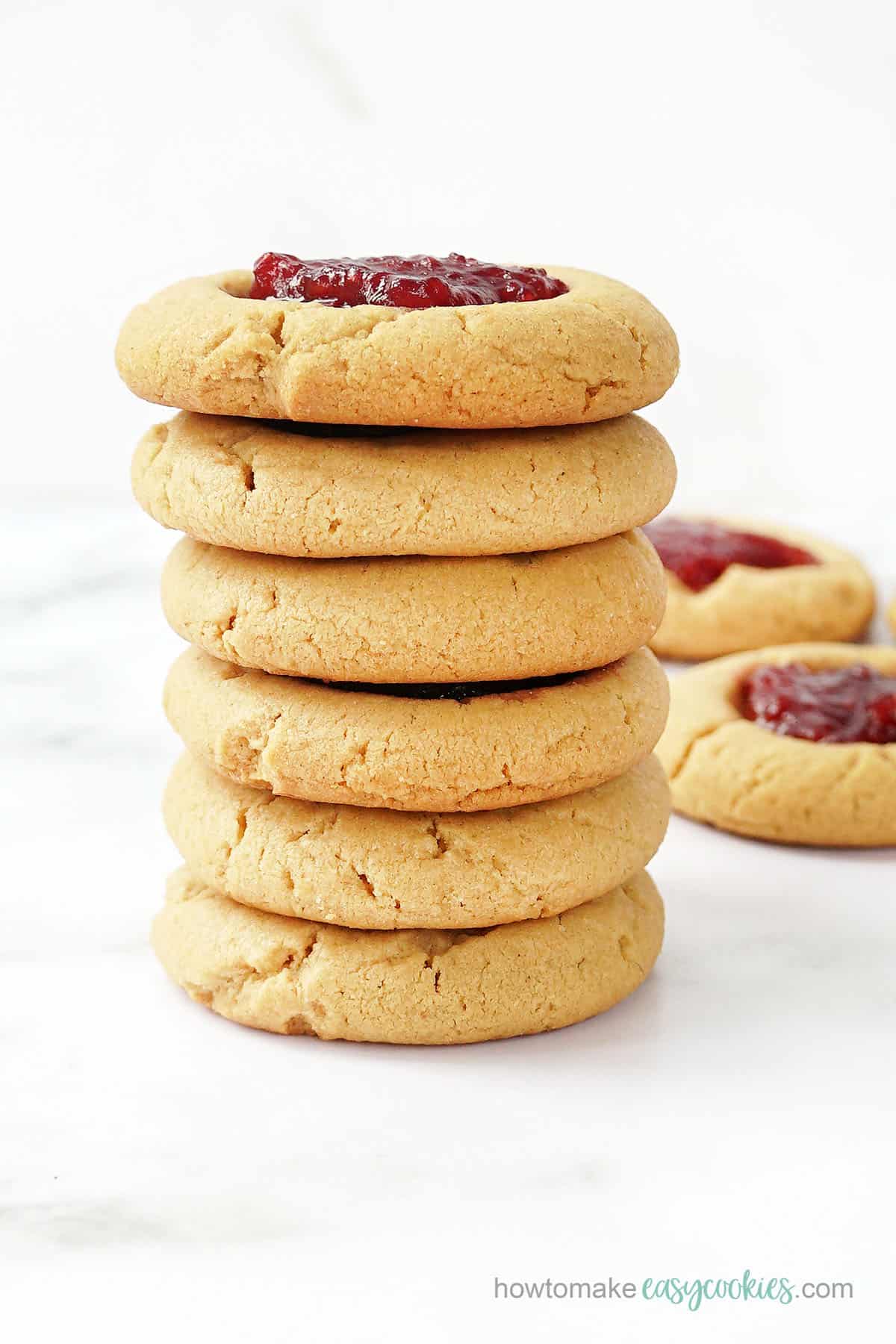 stack of peanut butter thumbprint cookies with raspberry jam 