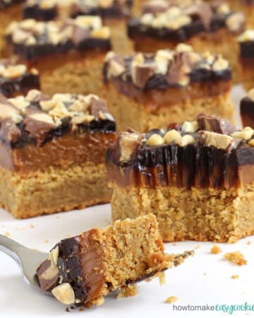 caramel peanut butter cookie bars topped with Dulce de Leche, chocolate ganache, peanuts, and Reese's Cups