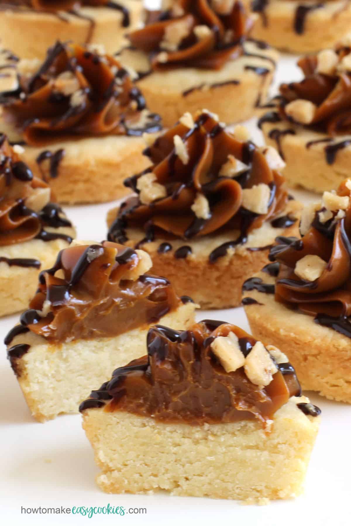 caramel shortbread cookie cups topped with Dulce de Leche, chocolate sauce, and toffee bits