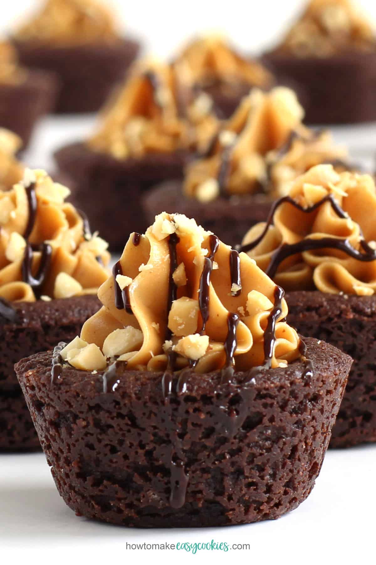 chocolate peanut butter cookie cups topped with peanut butter, chocolate, and peanuts