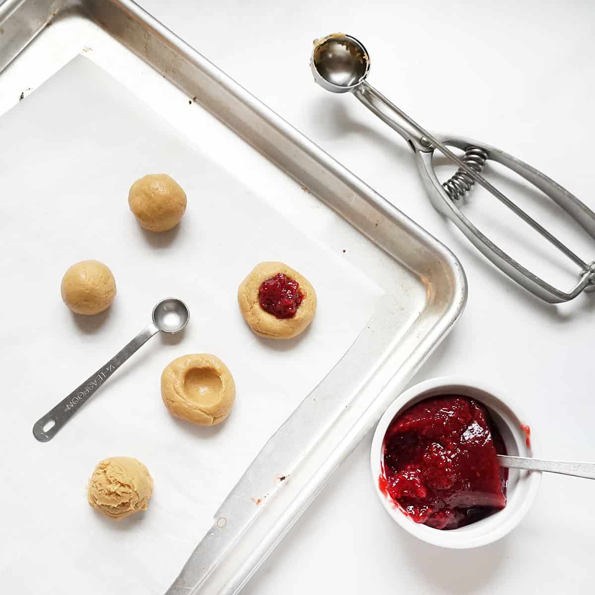 filling peanut butter thumbprint cookies with raspberry jam
