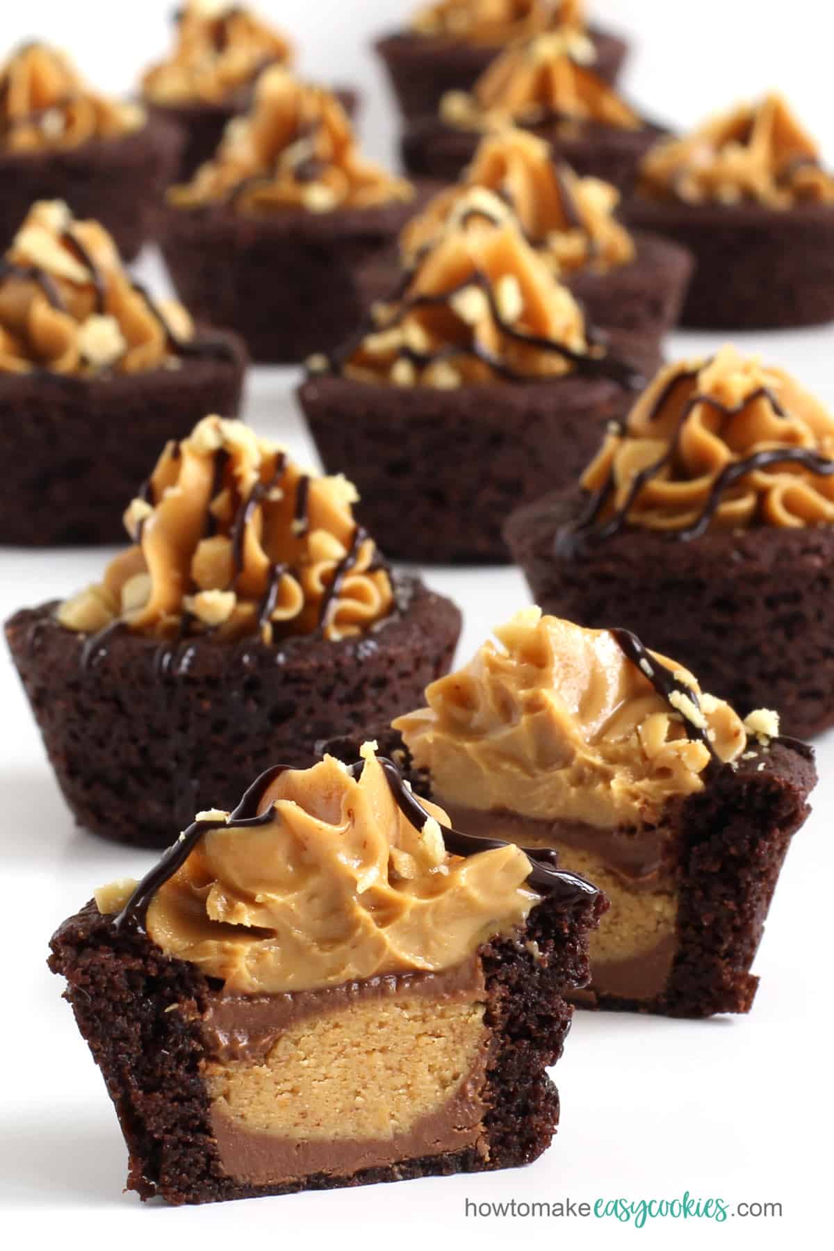 Reese's peanut butter cookie cups stuffed with a Reese's cup and topped with peanut butter, chocolate sauce, and peanuts