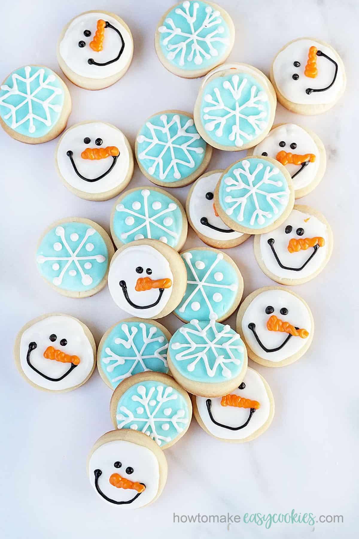 mini snowman and snowflake decorated Christmas sugar cookies with powdered sugar