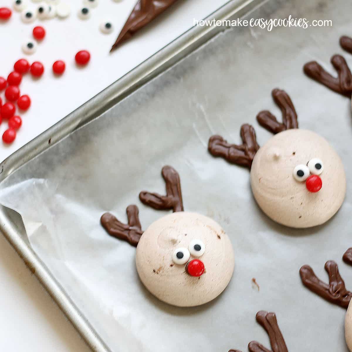 Decorating peppermint chocolate meringue cookies as Rudolph reindeer