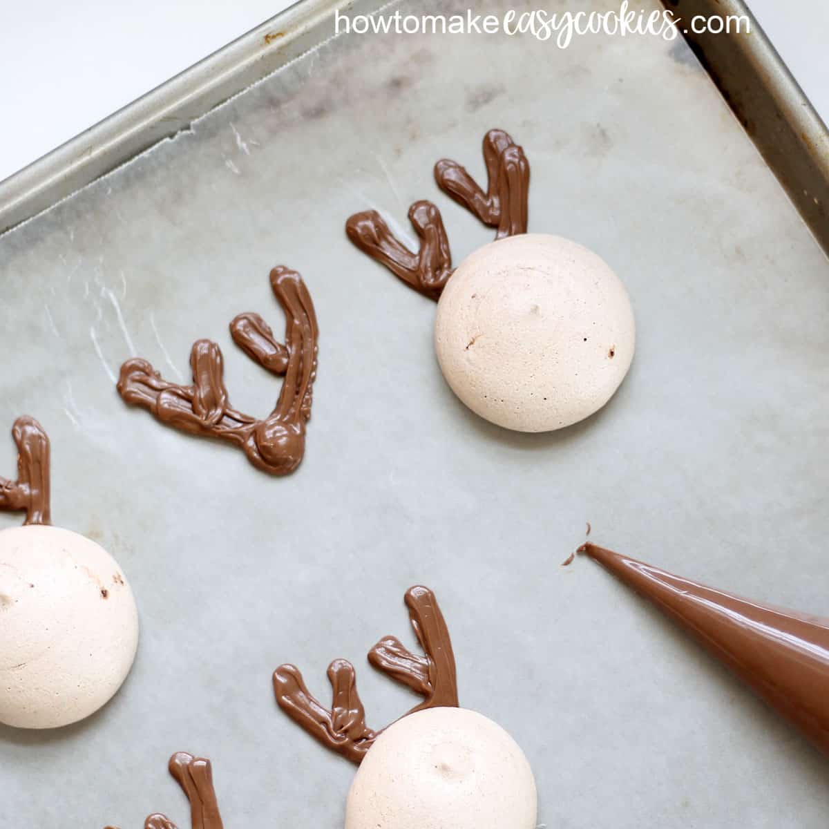 Piping chocolate for reindeer meringue Christmas cookies