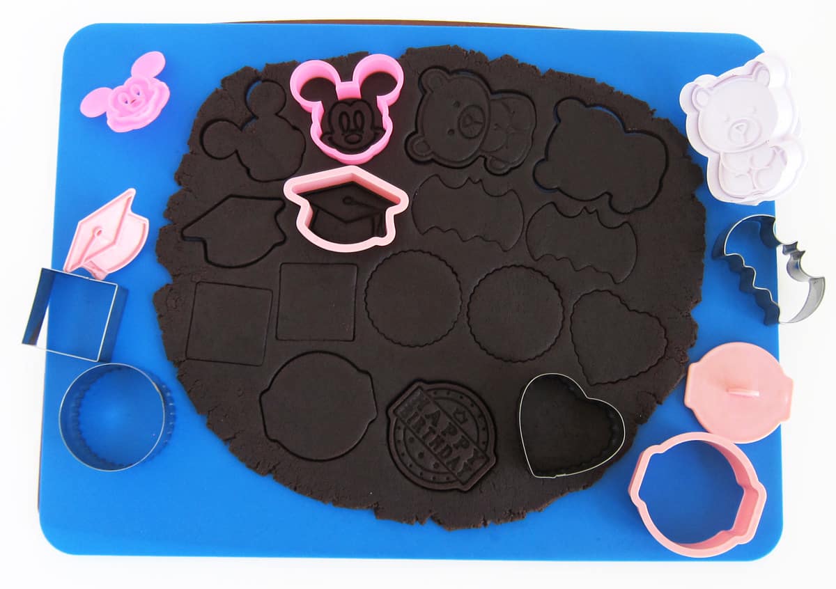 cutting out chocolate cookie dough using cookie stamps and cookie cutters