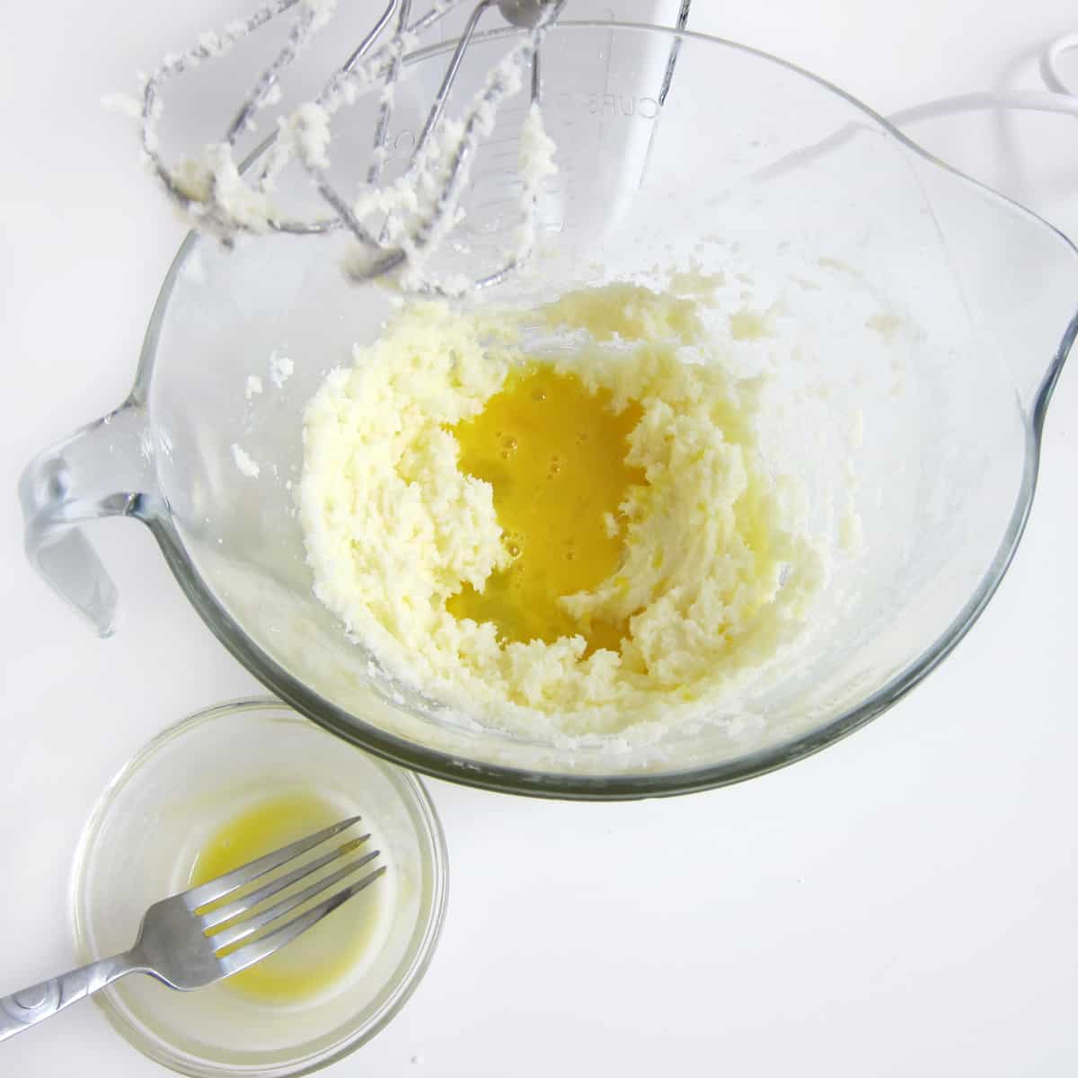 beaten egg poured on top of beaten butter and sugar in mixing bowl