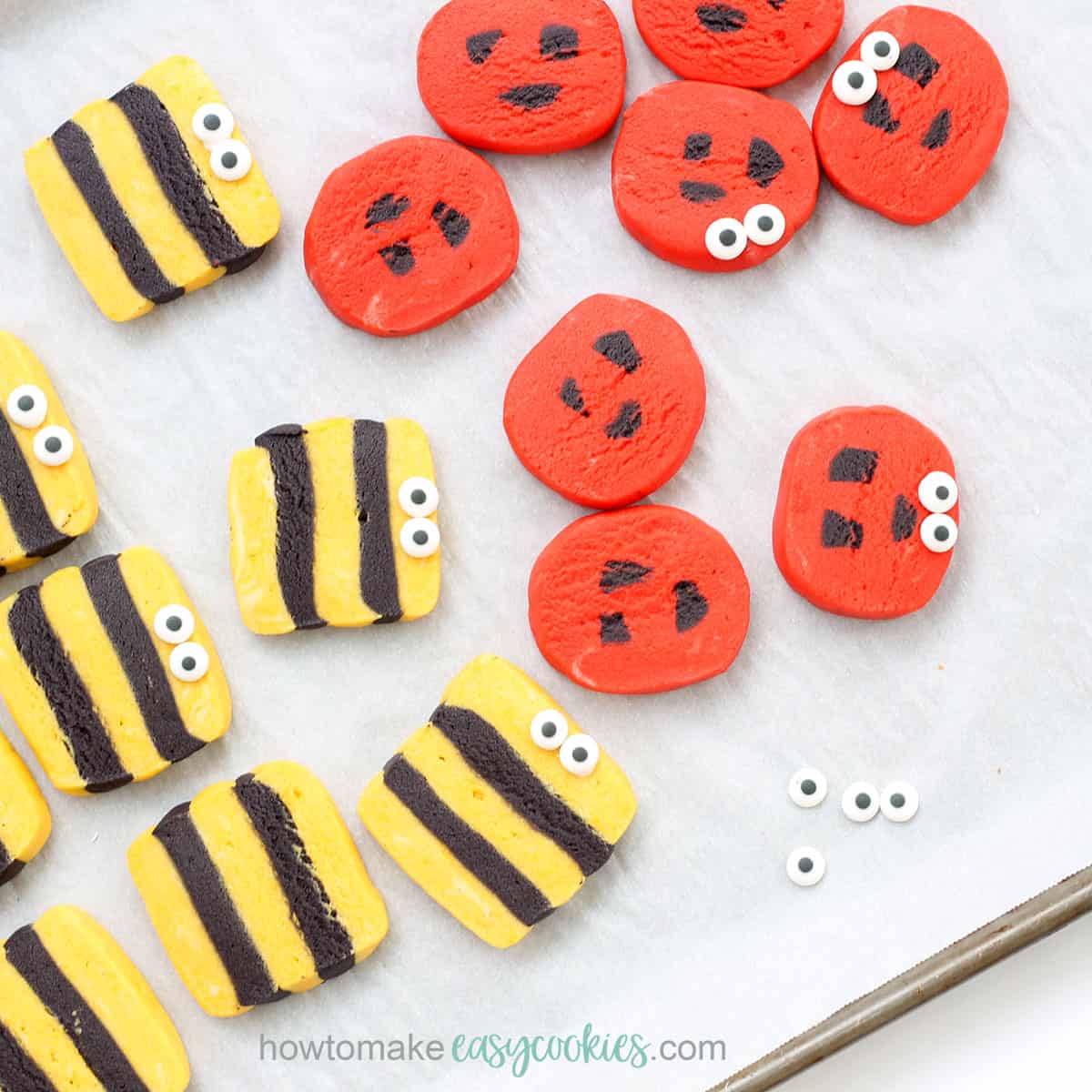 ladybug and bumble bee cookies with candy eyes on baking tray