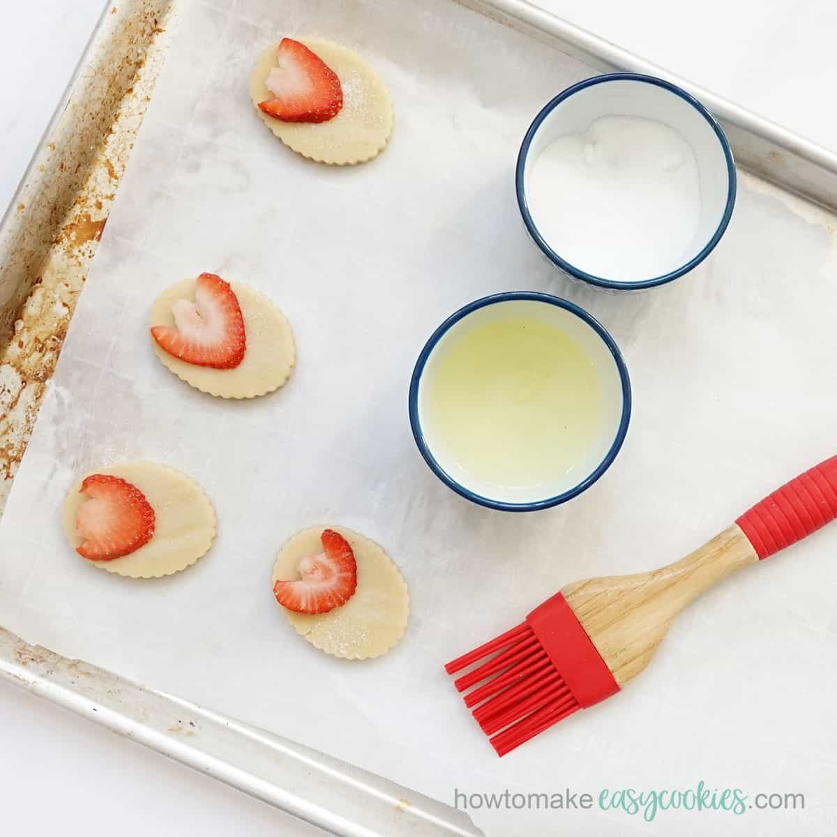Brushing egg wash and sugar on strawberry shortbread cookies