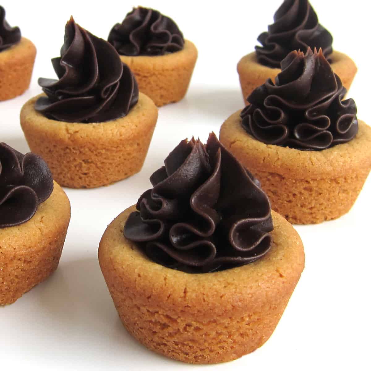 peanut butter cookie cups topped with a swirl of chocolate ganache frosting.