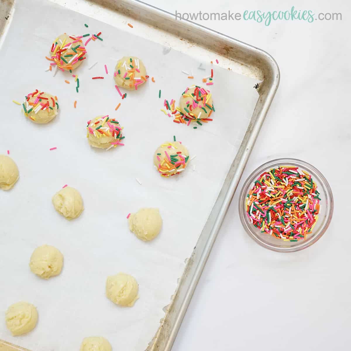 rolling white cake mix cookies in rainbow sprinkles
