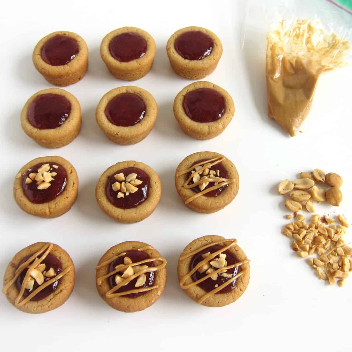 pb&j cookie cups topped with strawberry jam, chopped peanuts, and a drizzle of peanut butter