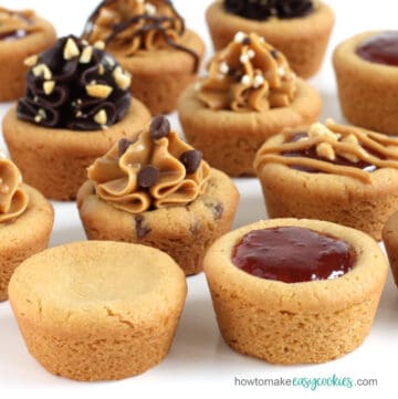 peanut butter cookie cups topped with a variety of ingredients like jelly, peanut butter, and chocolate frosting