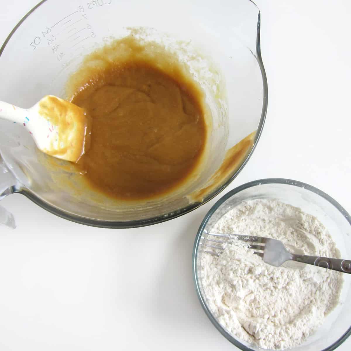 peanut butter cookie dough ingredients with wet ingredients mixed in one bowl and the dry ingredients mixed in another bowl