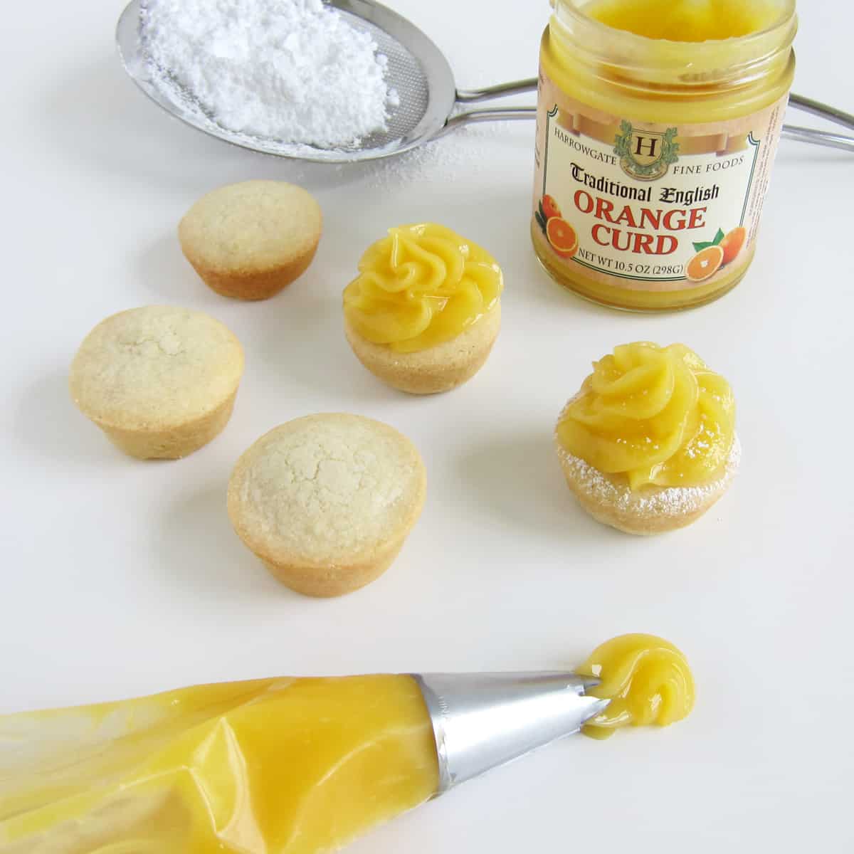 Pipe orange curd on sugar cookie cups then dust with powdered sugar.