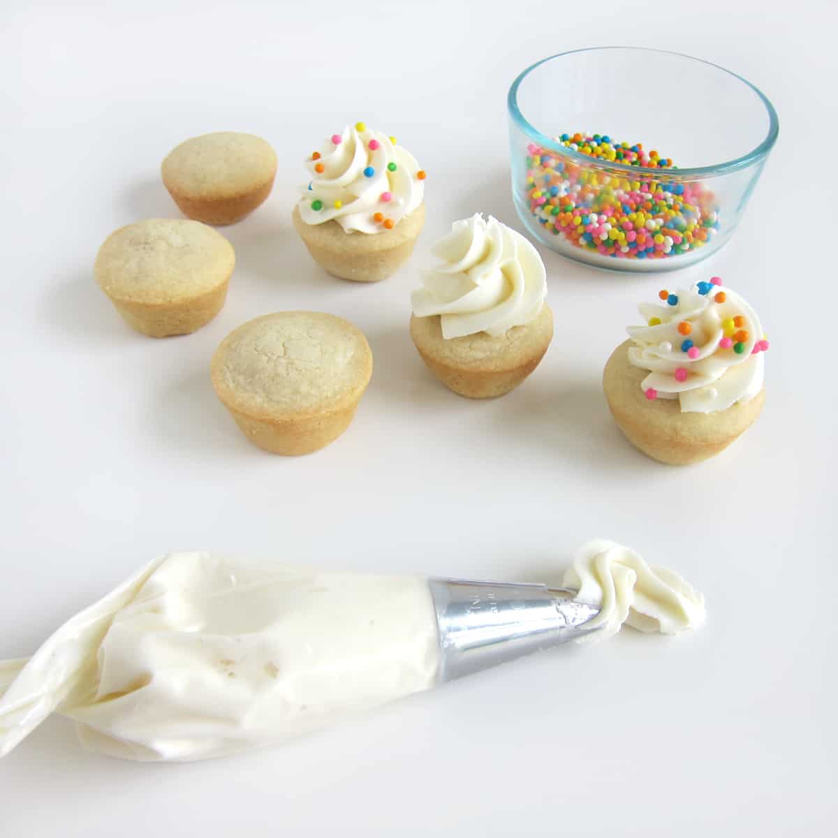 Pipe a swirl of vanilla frosting on top of sugar cookie cups then add rainbow Crispearls.