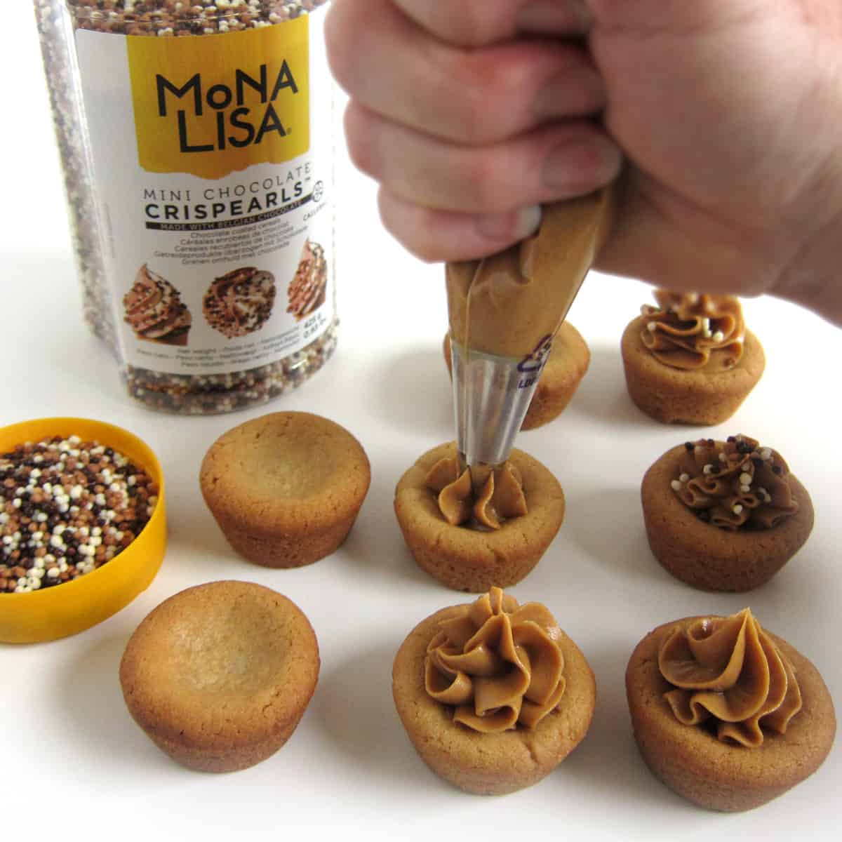 topping peanut butter cookie cups with peanut butter and Mona Lisa chocolate Crispearls