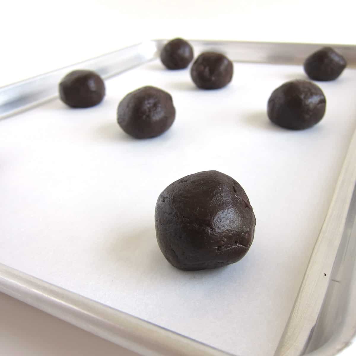 Brownie mix cookie dough balls on a parchment paper-lined baking sheet.