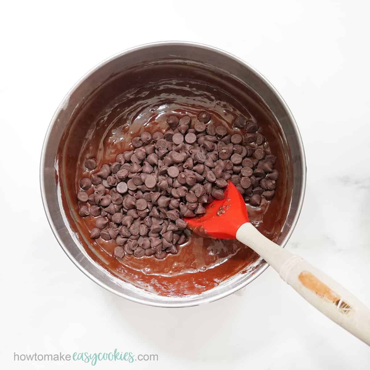 mixing chocolate chips into brownies batter